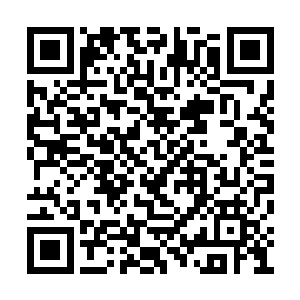 小孩在一旁给游客们介绍坐在帐篷前的那位男子二维码生成